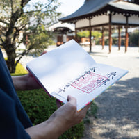 Person holding a book with Japanese text in a park setting